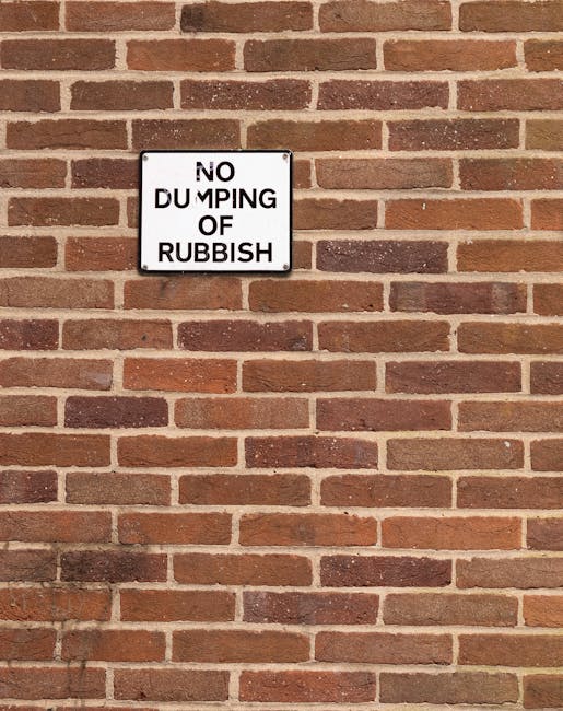 A collection of black and dark grey rubbish bags filled with waste materials piled against a red metal door that has various graffiti tags and stickers, including a white sign reading 'No Money' and a